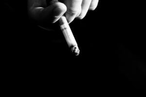 下向きに持たれたタバコと手が映るモノクロ写真