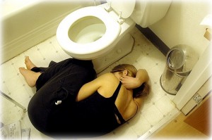 トイレの床で横たわる黒いドレスの女性
